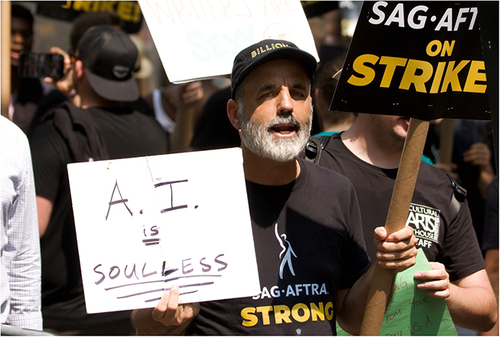 Photograph from the Screen Actors Guild of America strike in New York City with a protester holding a sign that reads: “AI is soulless!”